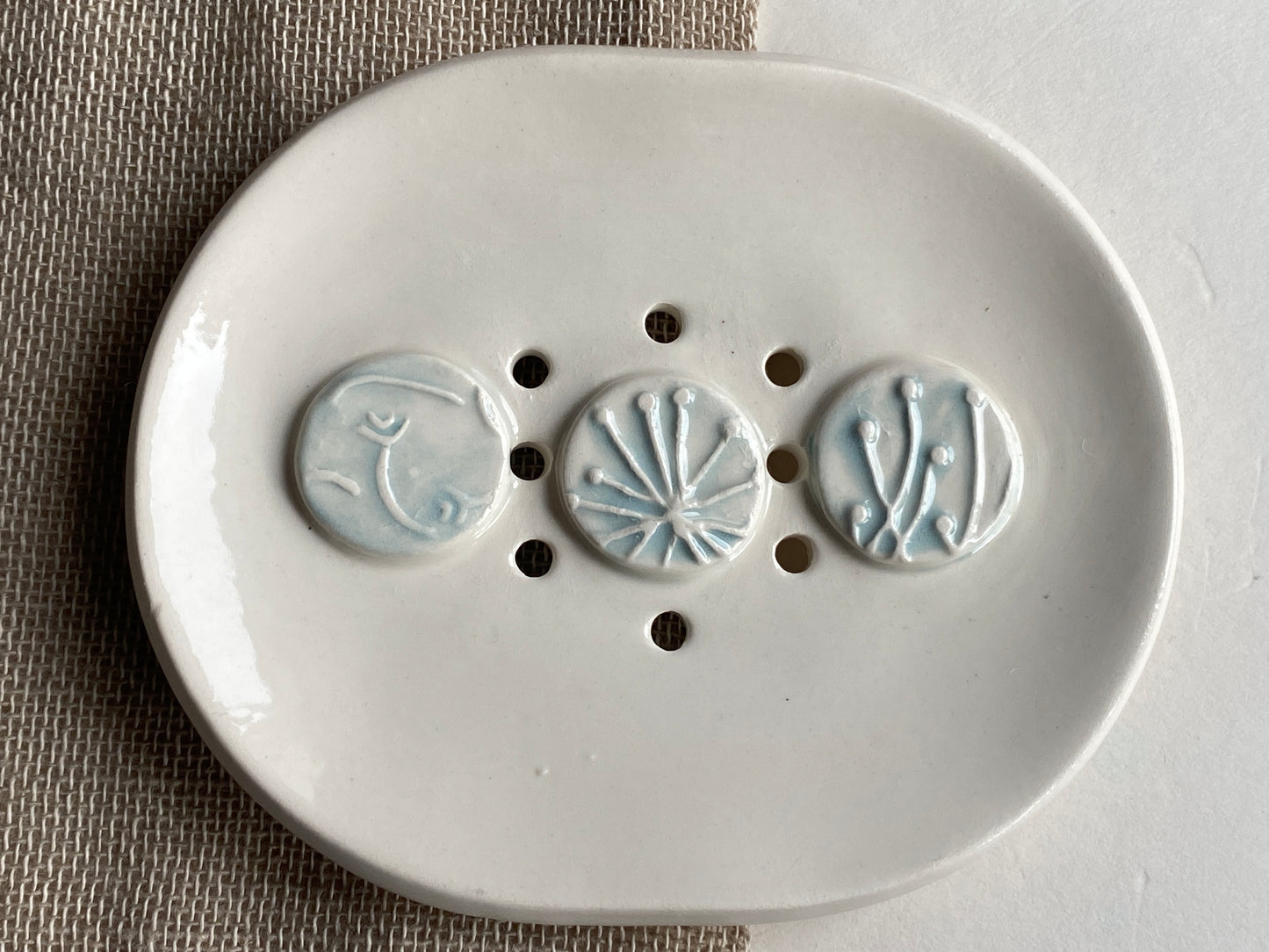 handmade ceramic soap dish with drainage holes. white with pale blue botanical details